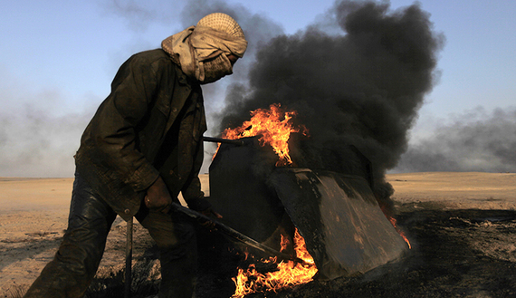 A man works at a makeshift oil refinery site in Raqqa's countryside, May 5, 2013.